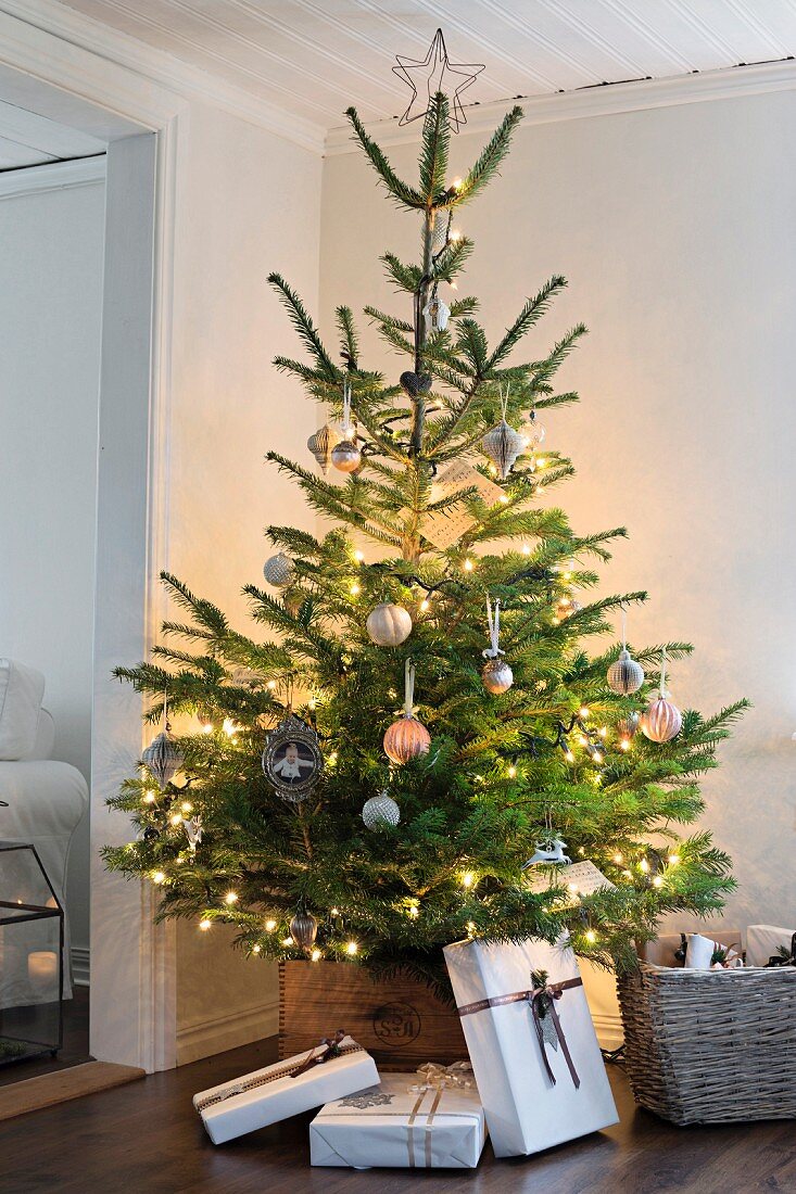 Beleuchteter Weihnachtsbaum mit schlicht verpackten Geschenken