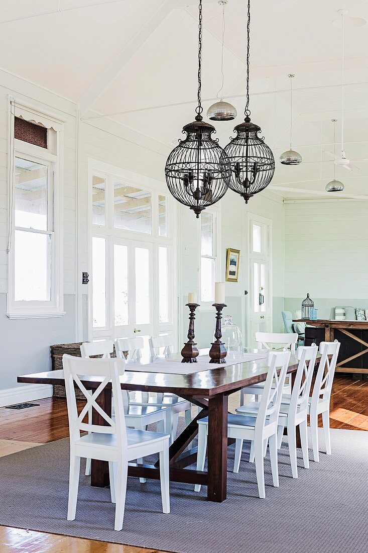 White wooden chairs around wooden table, metal chandelier in the dining area with nostalgic flair