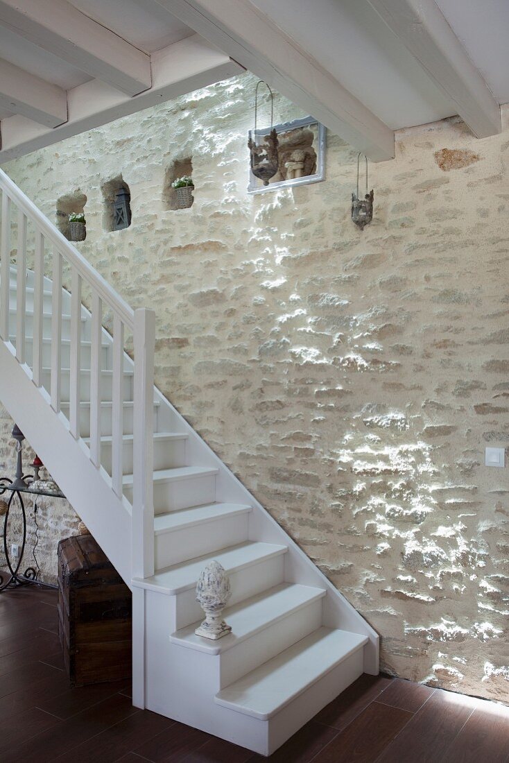 Weiß lackierte Holztreppe vor Natursteinwand