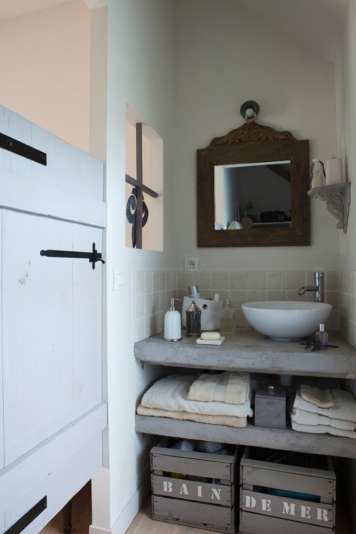 Betonierte Waschtischplatte mit weißer moderner Waschschüssel, darunter Ablage und Vintage Holzkisten