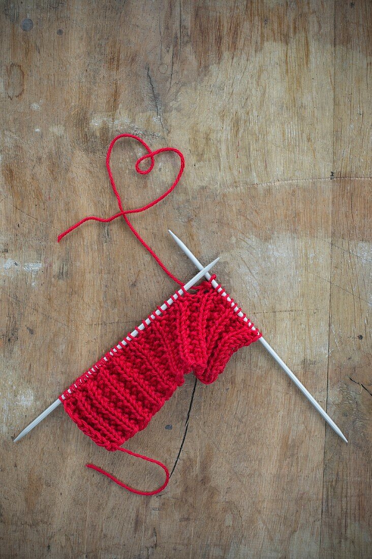 Knitting with red wool: yarn arranged in a love-heart