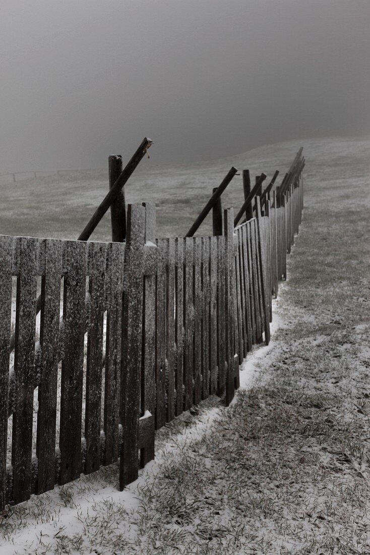 Hölzernes Schneefanggitter auf winterlicher Wiese