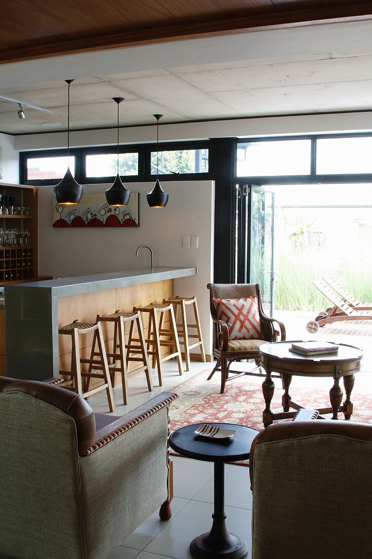 Gemütlicher Loungebereich mit Antikmöbeln und Küchentheke mit passenden Barhockern, Blick auf Terrasse