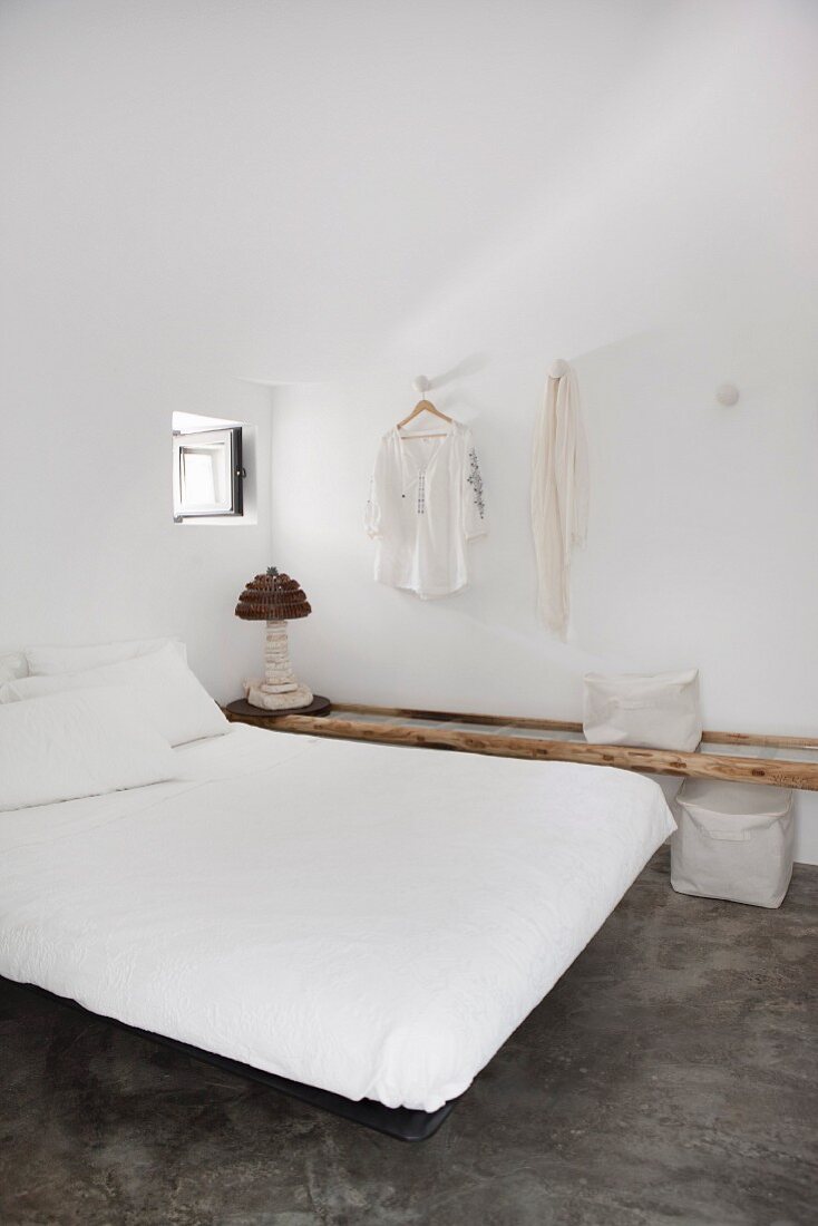 Simple double bed in minimalist bedroom with polished concrete floor