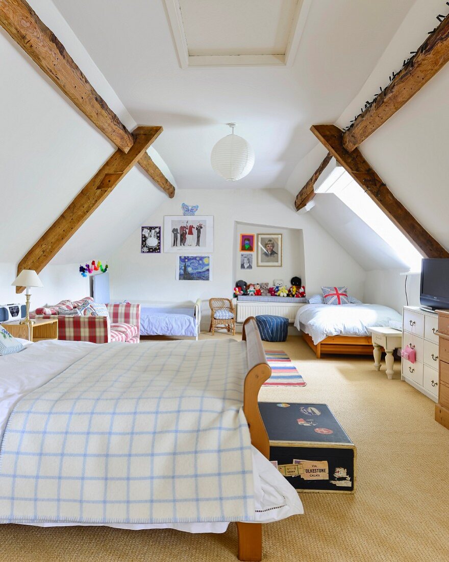 Schlafbereich mit mehreren Betten in ausgebautem Dachgeschoss und sichtbarer Holzbalkenkonstruktion
