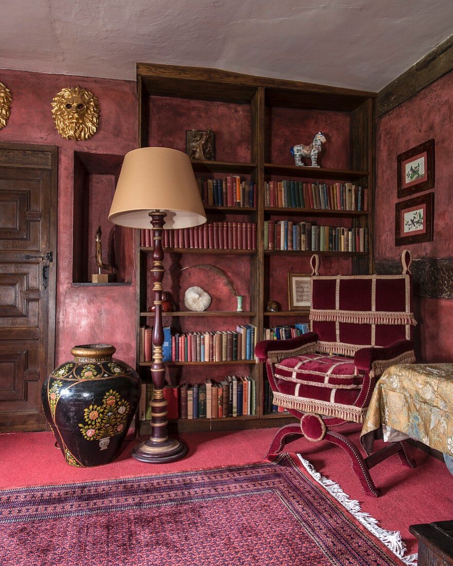 Standard lamp, velvet reading chair and bookcase in grand library
