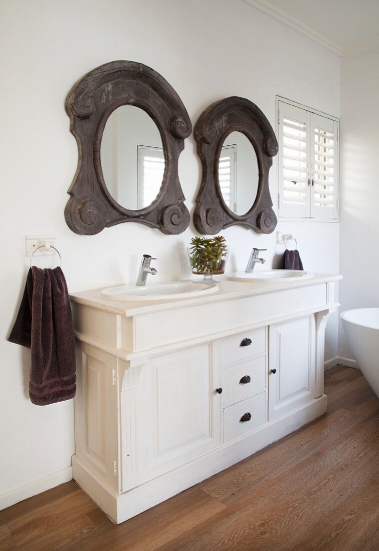 White washstand with rustic, ornate, wood-framed mirrors in country-house interior
