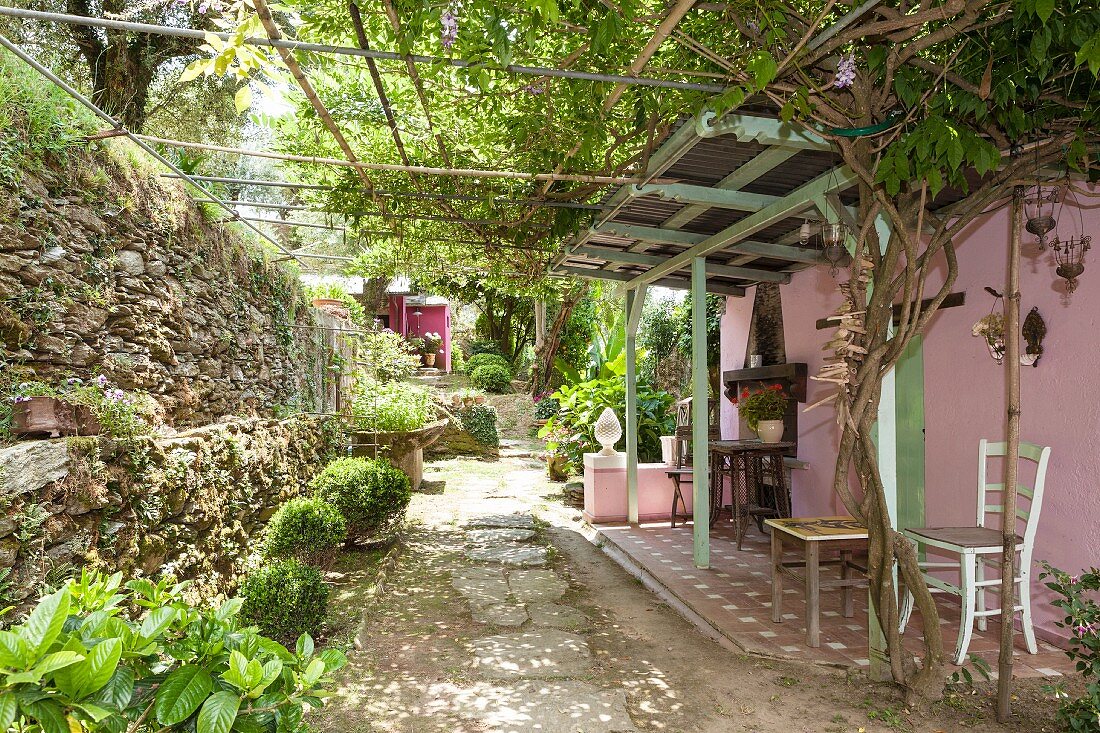 Climber-covered pergola and pink façade on Mediterranean terrace