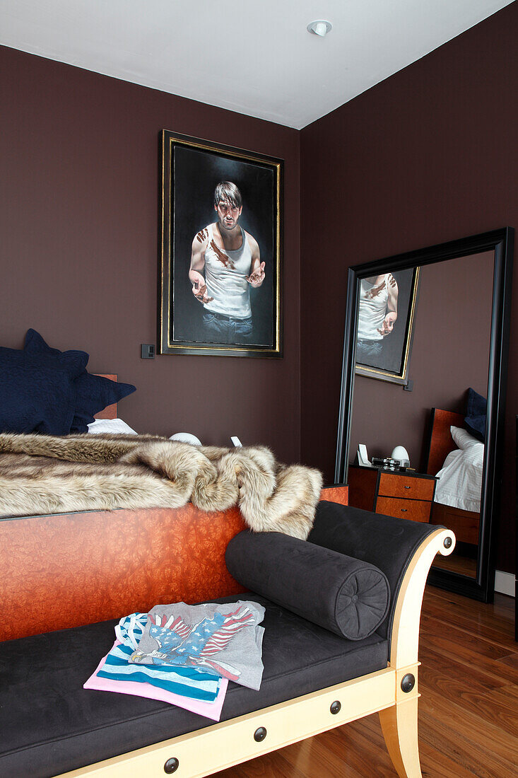 Upholstered bench at foot of bed in bedroom with brown walls