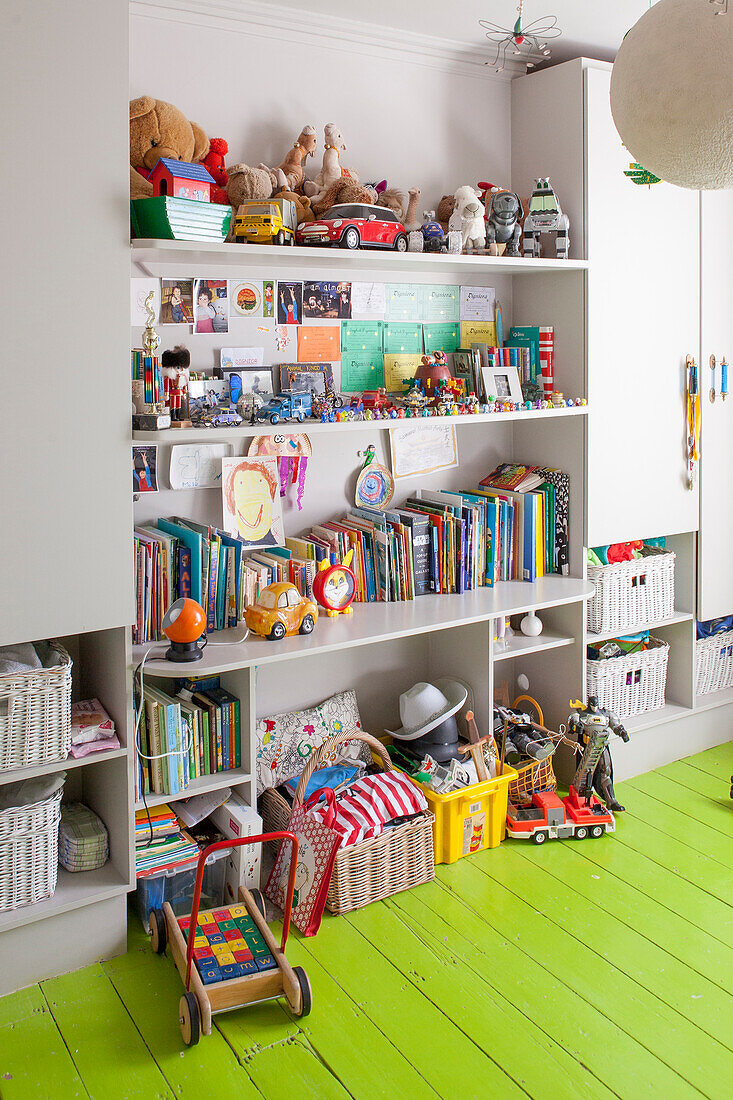 Shelves of toys in child's bedroom with green wooden floor