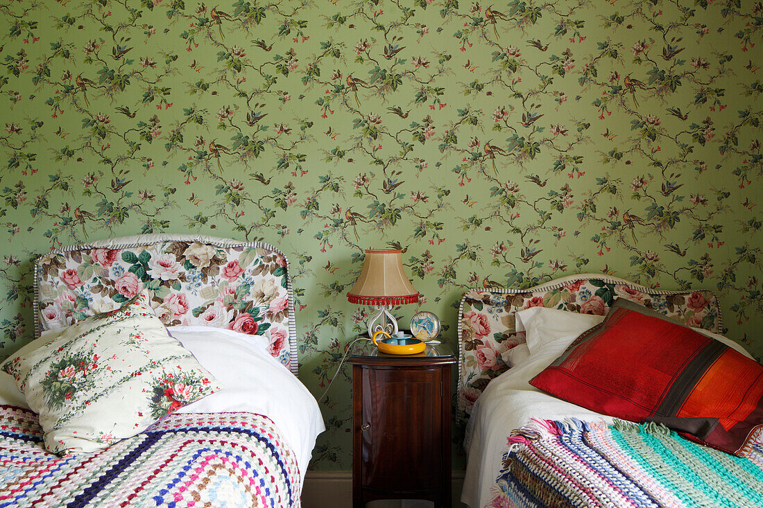 Twin beds with crocheted blankets against floral wallpaper