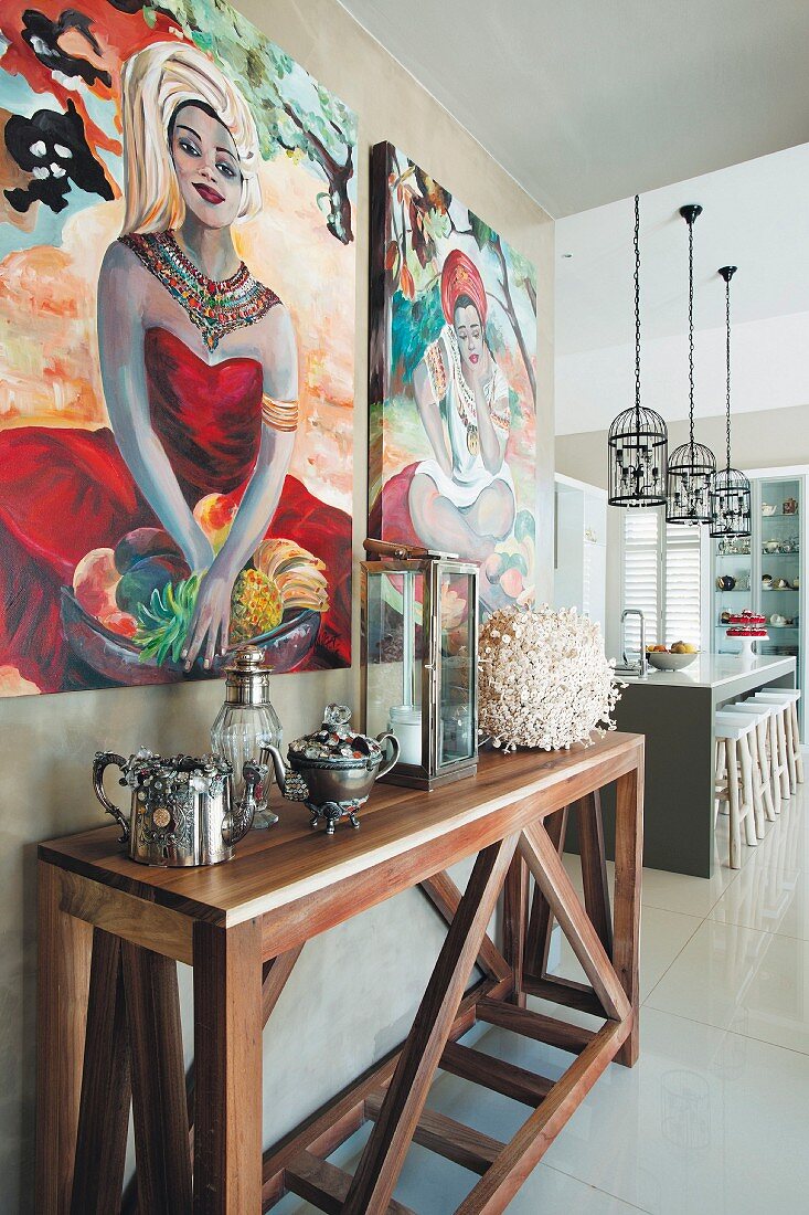 Sammlerstücke auf Wandtisch aus Holz vor Bildern an Wand aufgehängt, im Hintergrund Theke