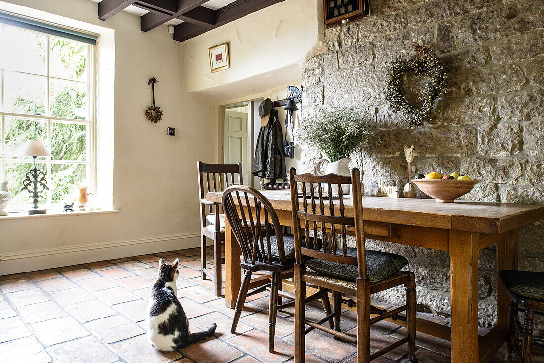 Various chairs at wooden table against stone wall