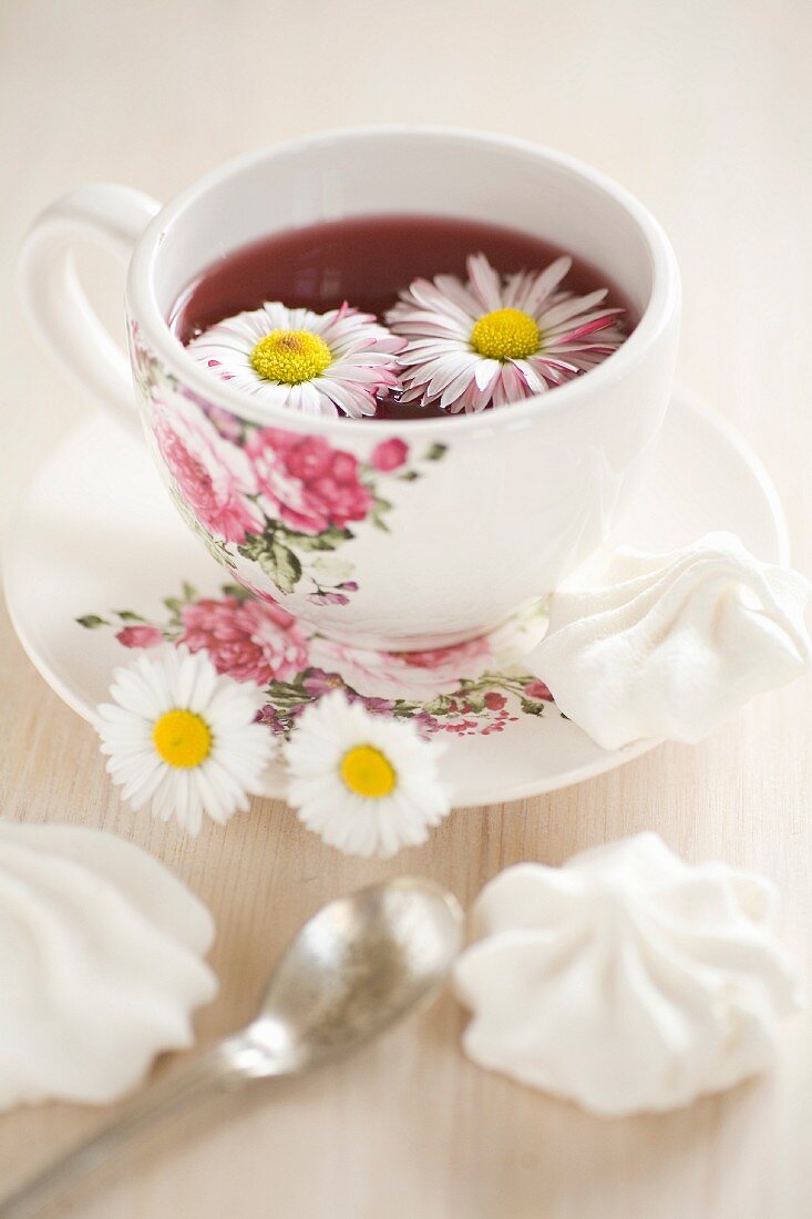 Tee mit Gänseblümchen in einer Tasse mit Blumenmuster