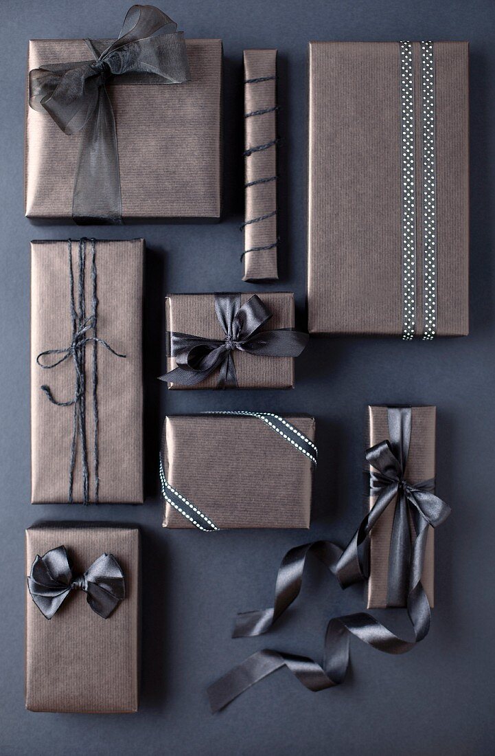 Mit grauem Papier und passenden Bändern als Geschenk eingepackte Schachteln
