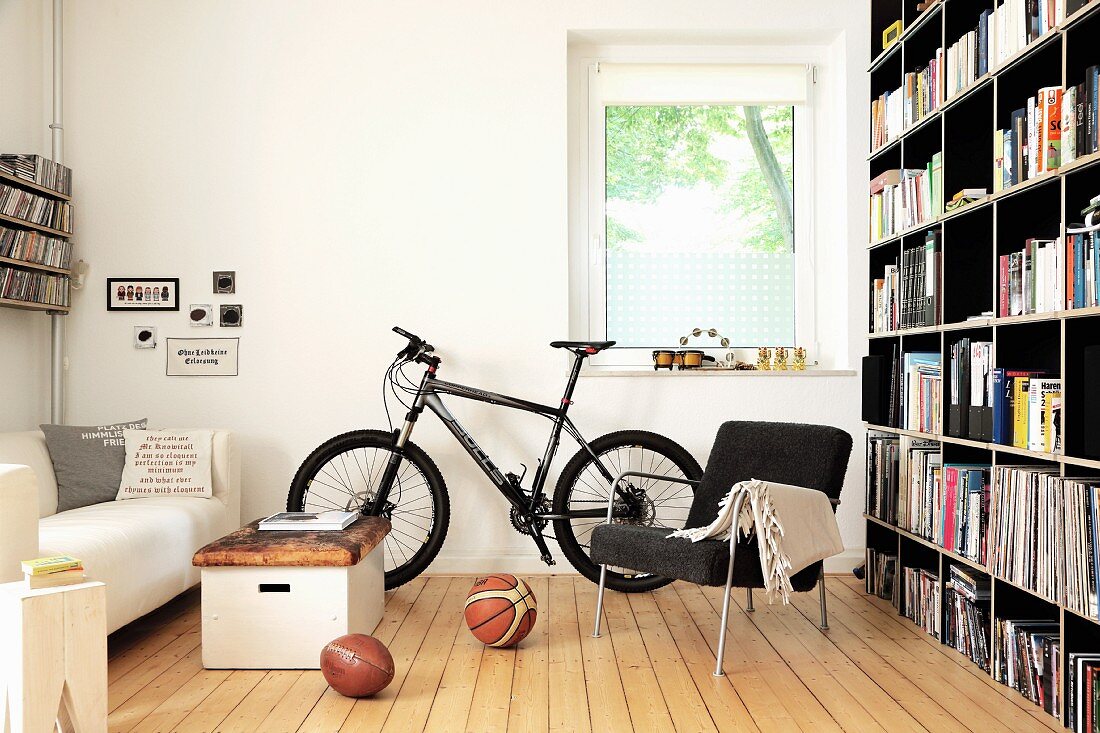 Bookcase, bicycles and old vaulting box used as coffee table in living room