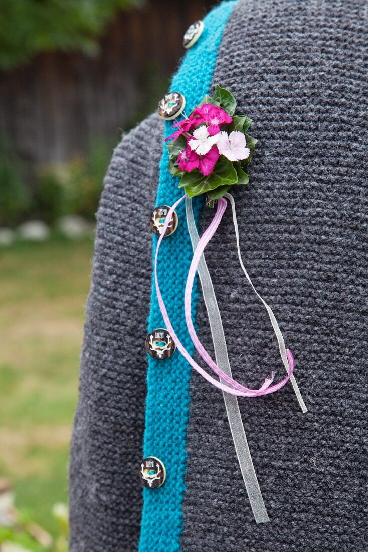 Buttonhole of Sweet William and ribbons pinned to traditional German cardigan