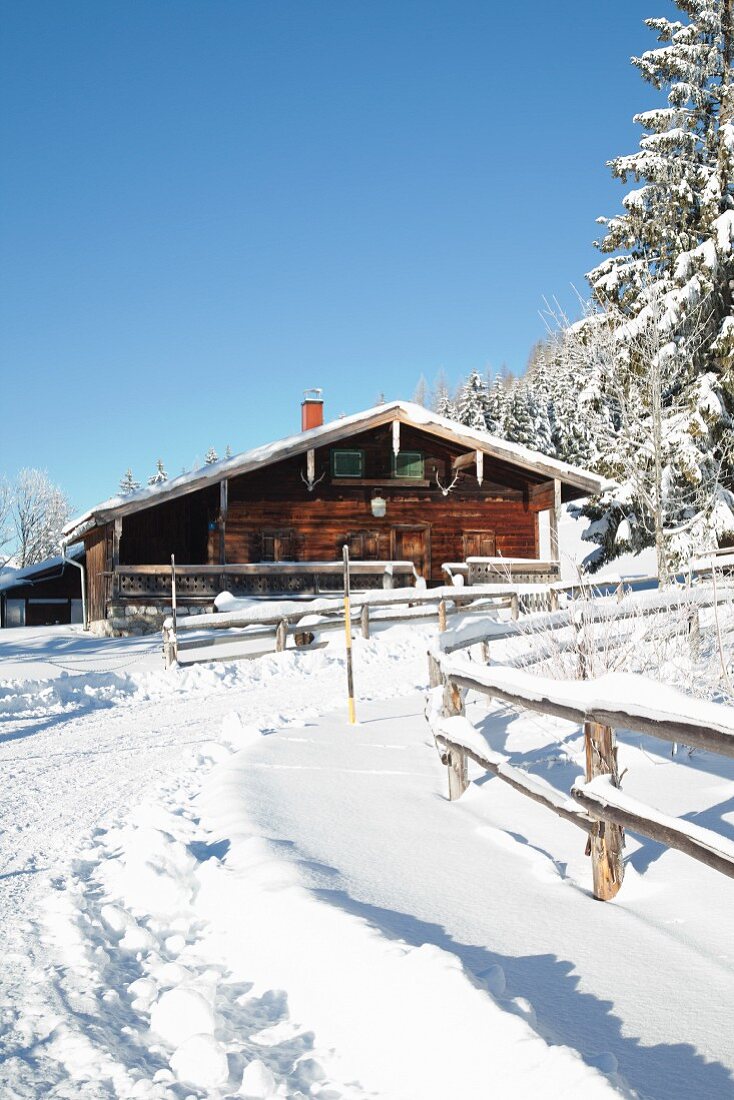 Alpine hut in snowy landscape below blue sky