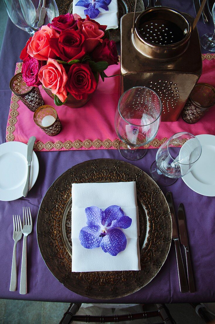 Festliches Gedeck mit Orchideenblüte auf indischer Hochzeitstafel