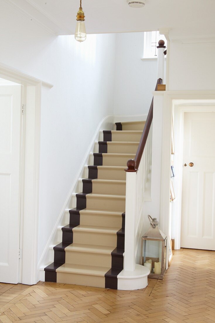 Restored wooden staircase painted white, brown and beige in white country-house foyer