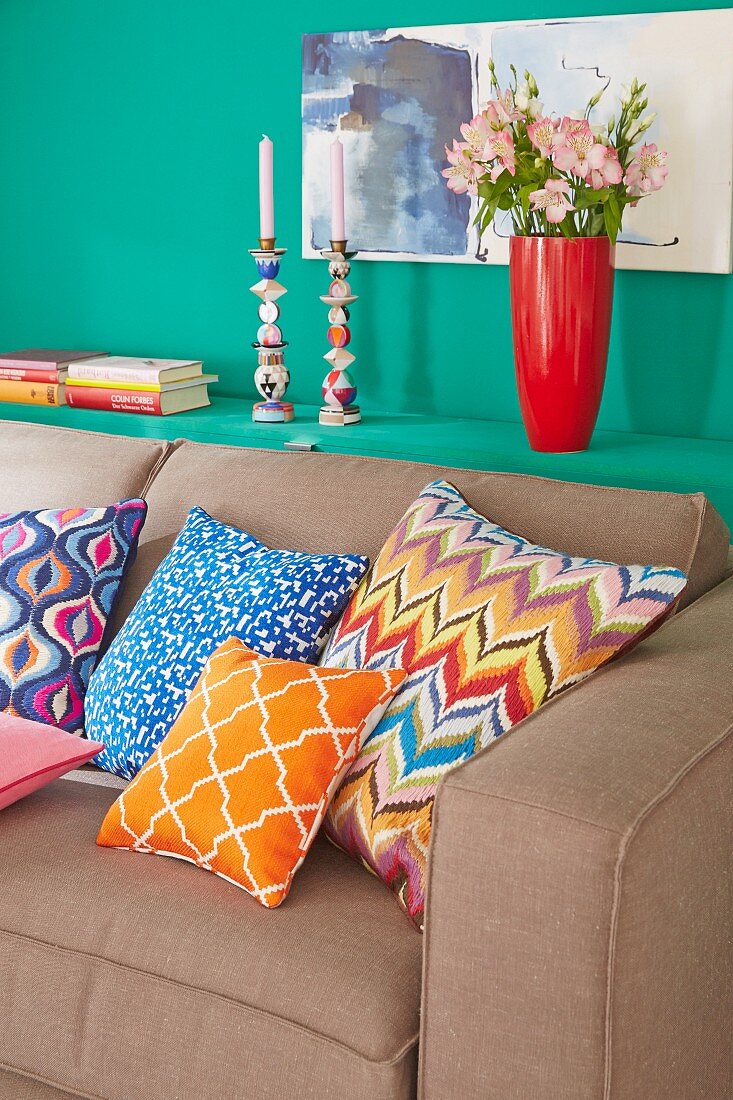 Colourful cushions on a sofa bed with storage space behind in an openable green shelf
