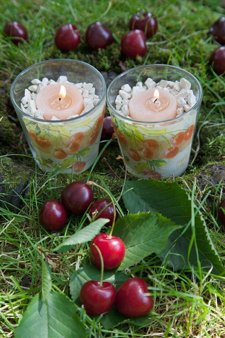 Tealight holders with patterns of cherries among cherries on grass