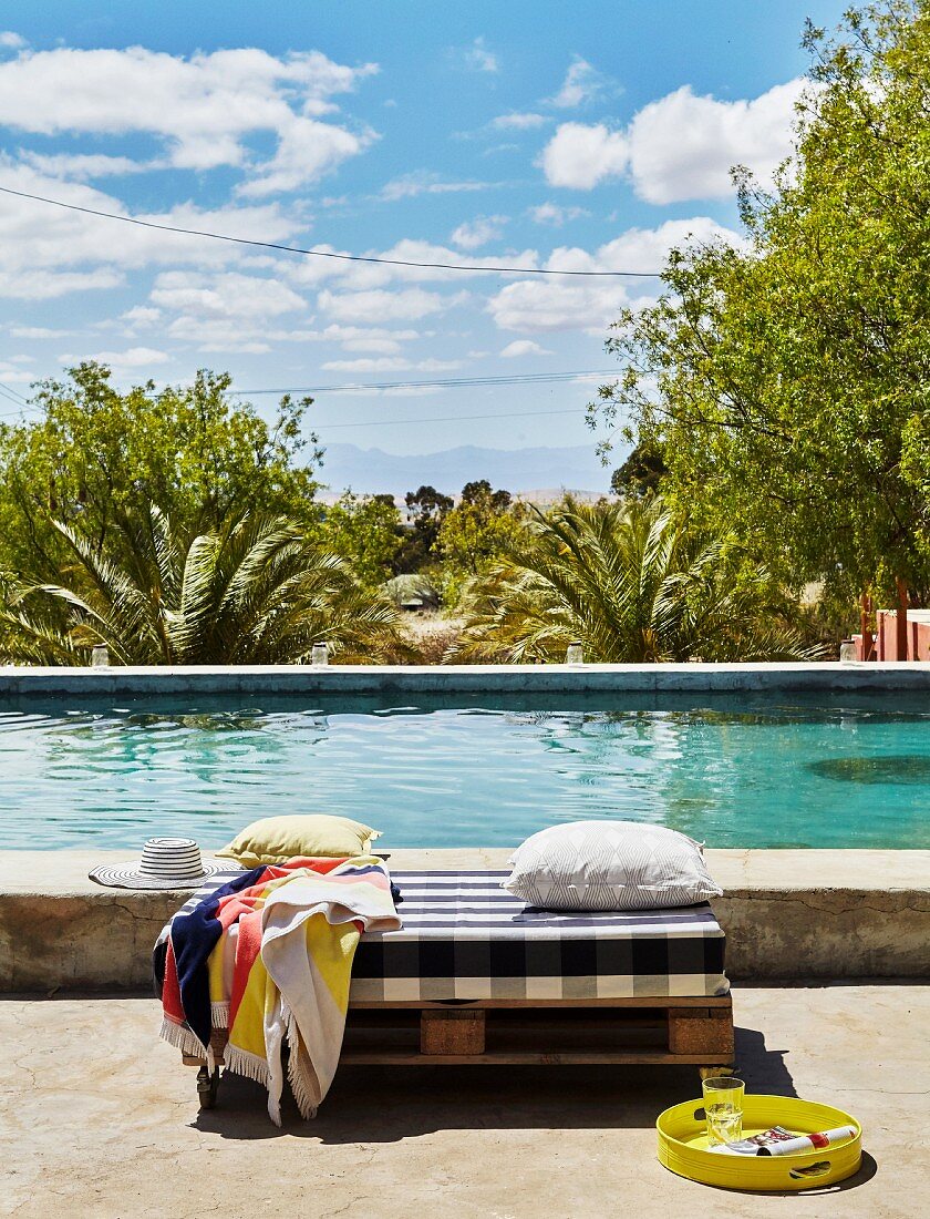 Floor cushions and scatter cushions on wooden pallet next to pool
