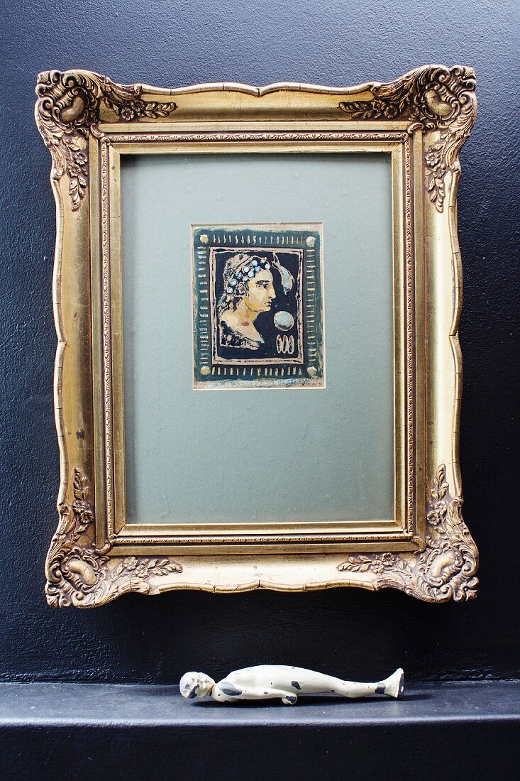 Antique picture in gilt frame above sculpture of supine figure