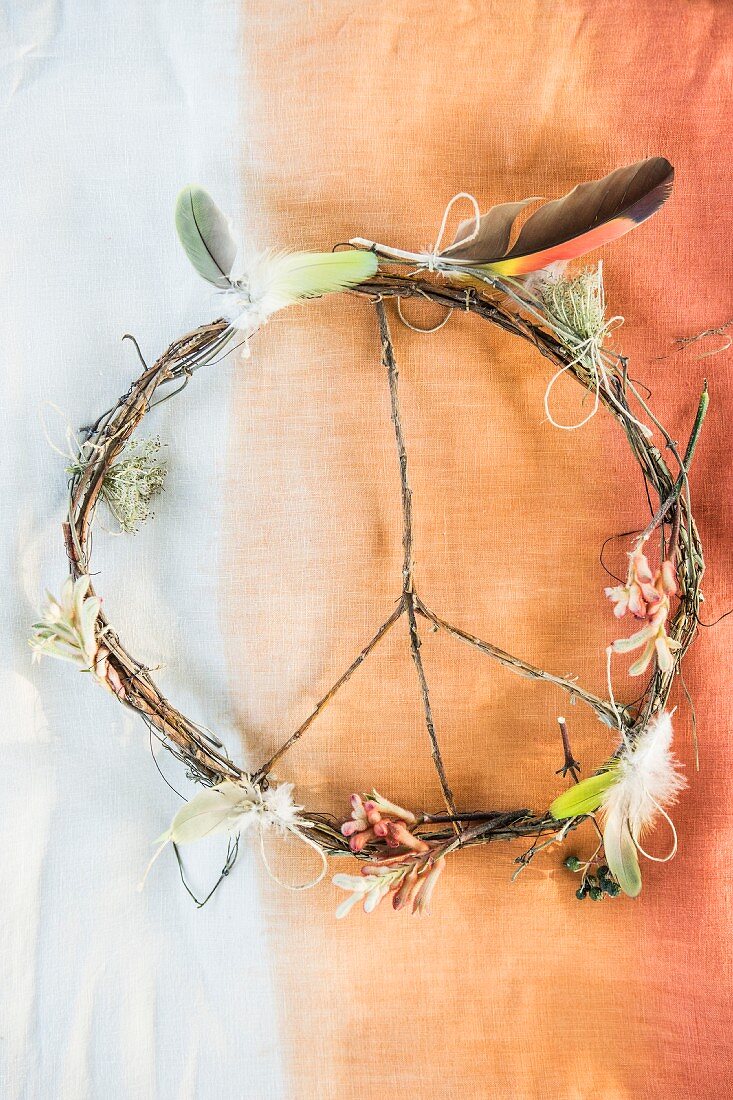 Peace sign made from twigs decorated with feathers and flowers