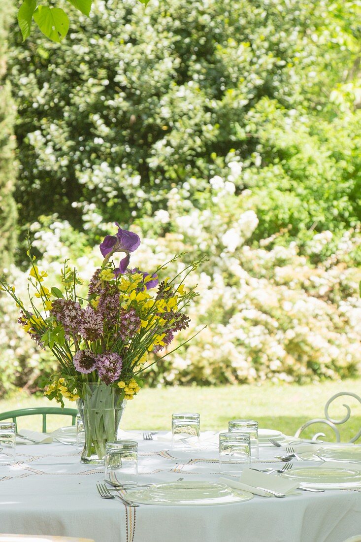 Weiß gedeckter Tisch im Freien mit prachtvollem Frühlingsblumenstrauss