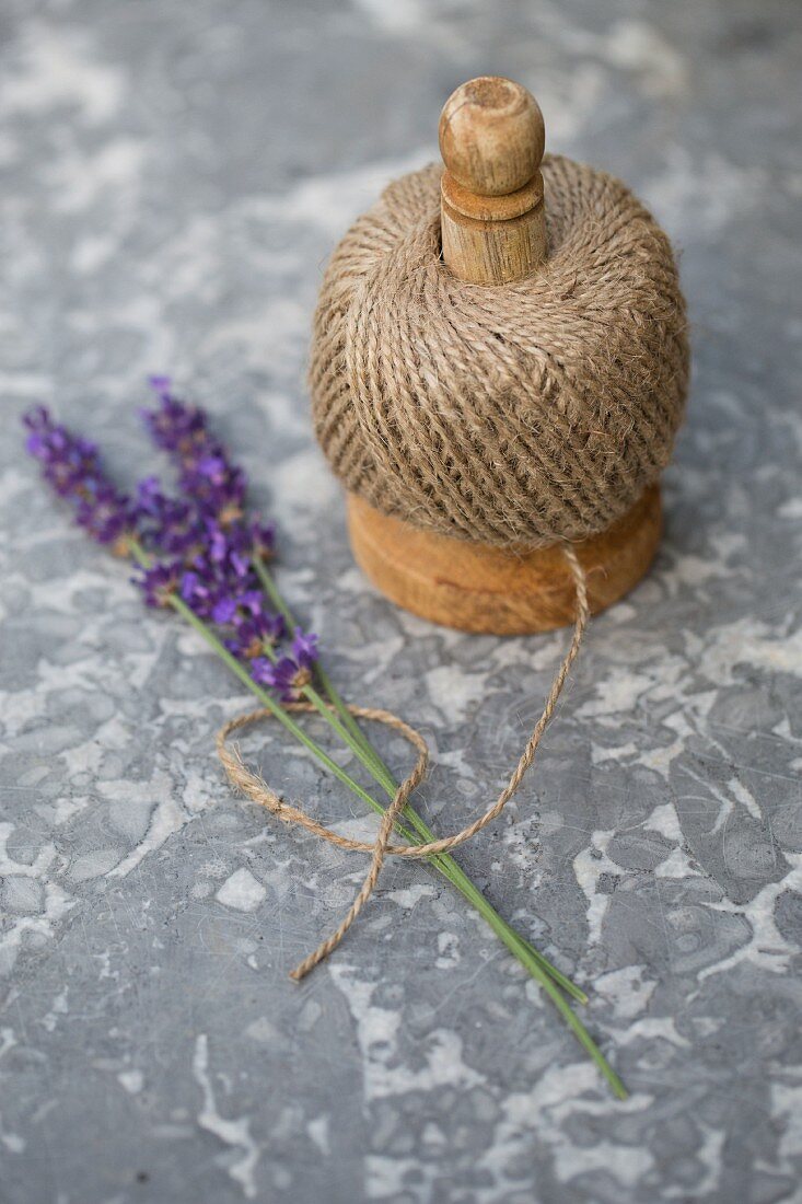 Schnurrolle mit Lavendelzweigen auf Marmorplatte