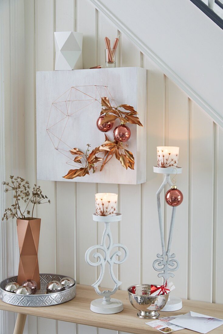 Copper-coloured Christmas decorations made from spray-painted twigs and baubles, tied to a string sculpture