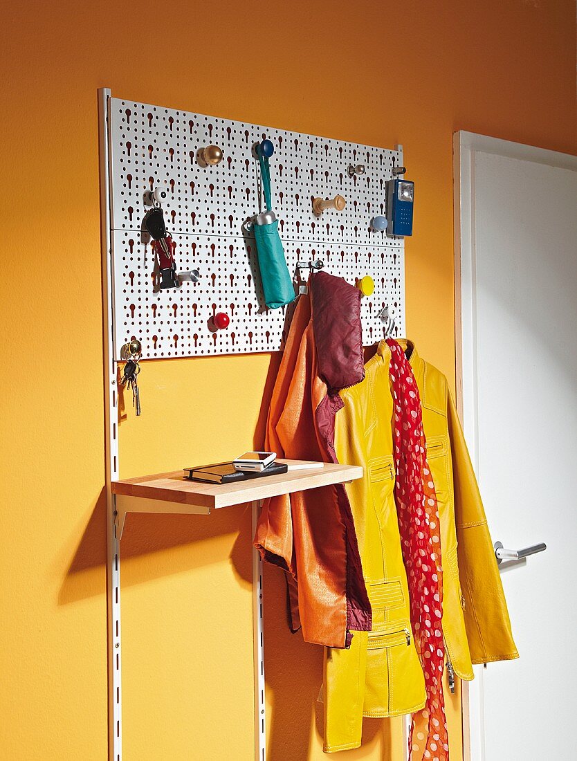 Coat rack made from perforated grid and colourful furniture knobs