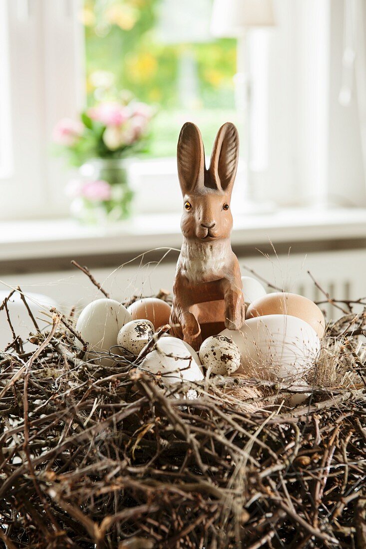 Hare figurine and eggs in Easter nest made from willow twigs