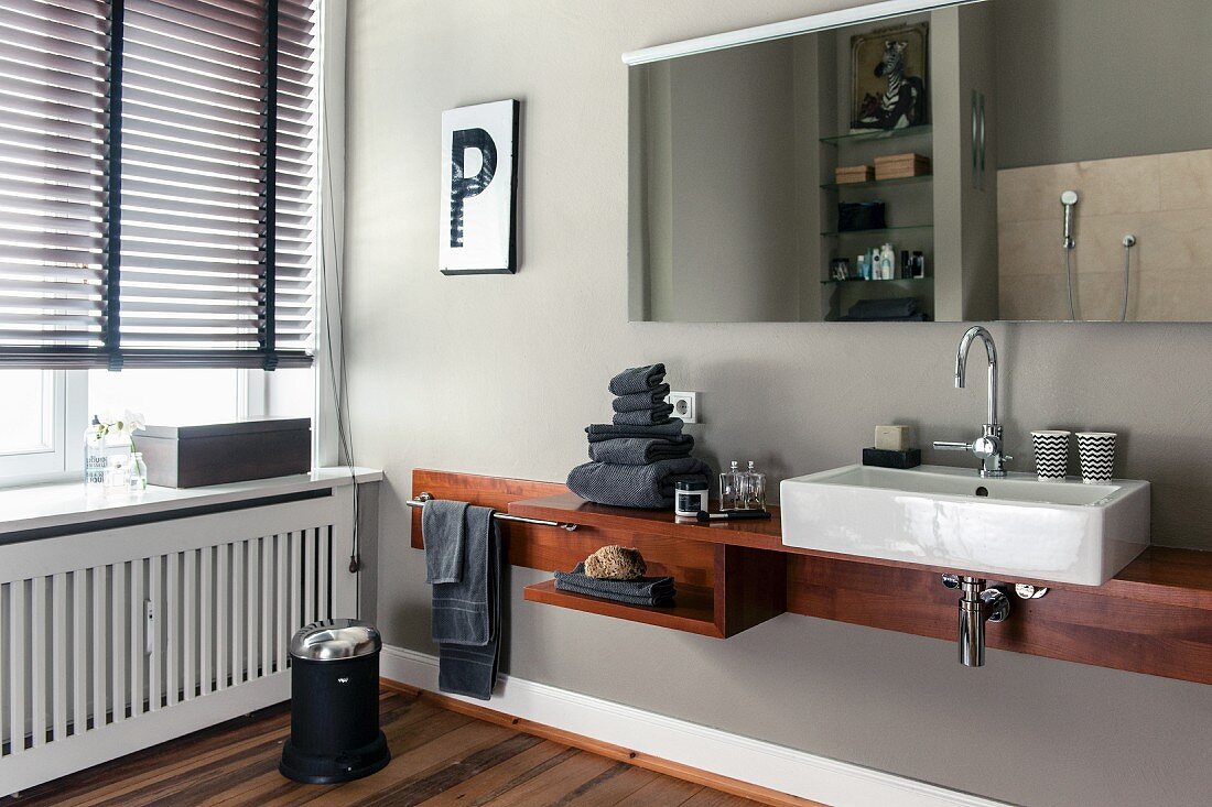 Massgefertigte Waschtischablage mit Porzellanwaschbecken, oberhalb Spiegel an hellgrauer Wand