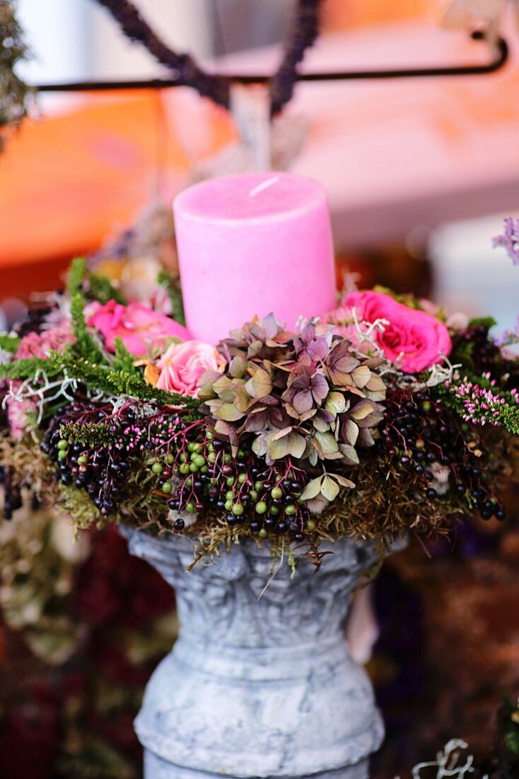 Kranz aus Hortensien, Rosen und Holunderbeeren mit rosa Kerze auf Kerzenständer