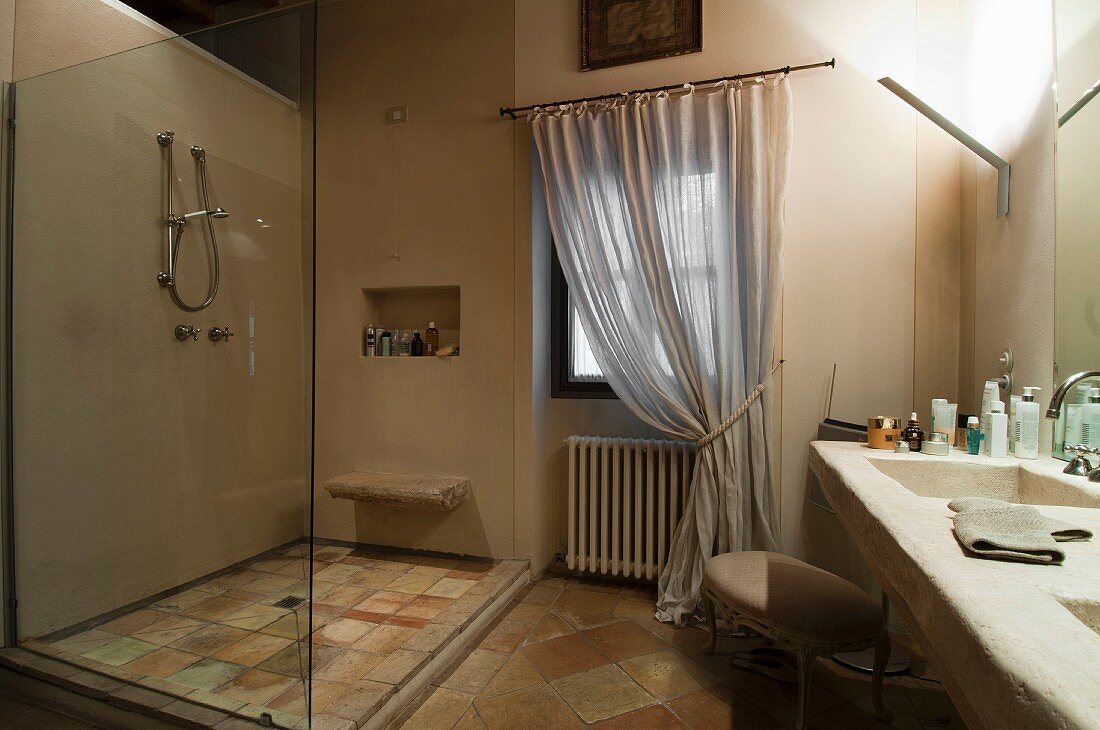 Dusche mit Glastrennscheibe, gegenüber gemauerte Waschtischzeile in ländlichem Bad