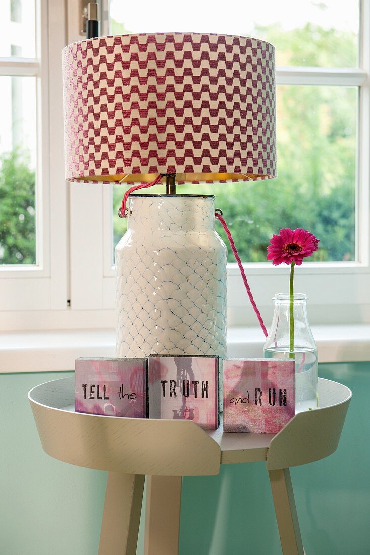 Table lamp with red and white zigzag lampshade and small framed mottoes on side table