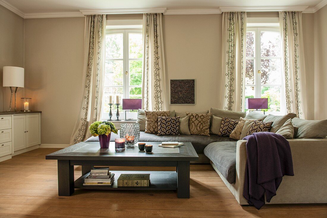 Coffee table and corner couch in front of windows in elegant beige interior