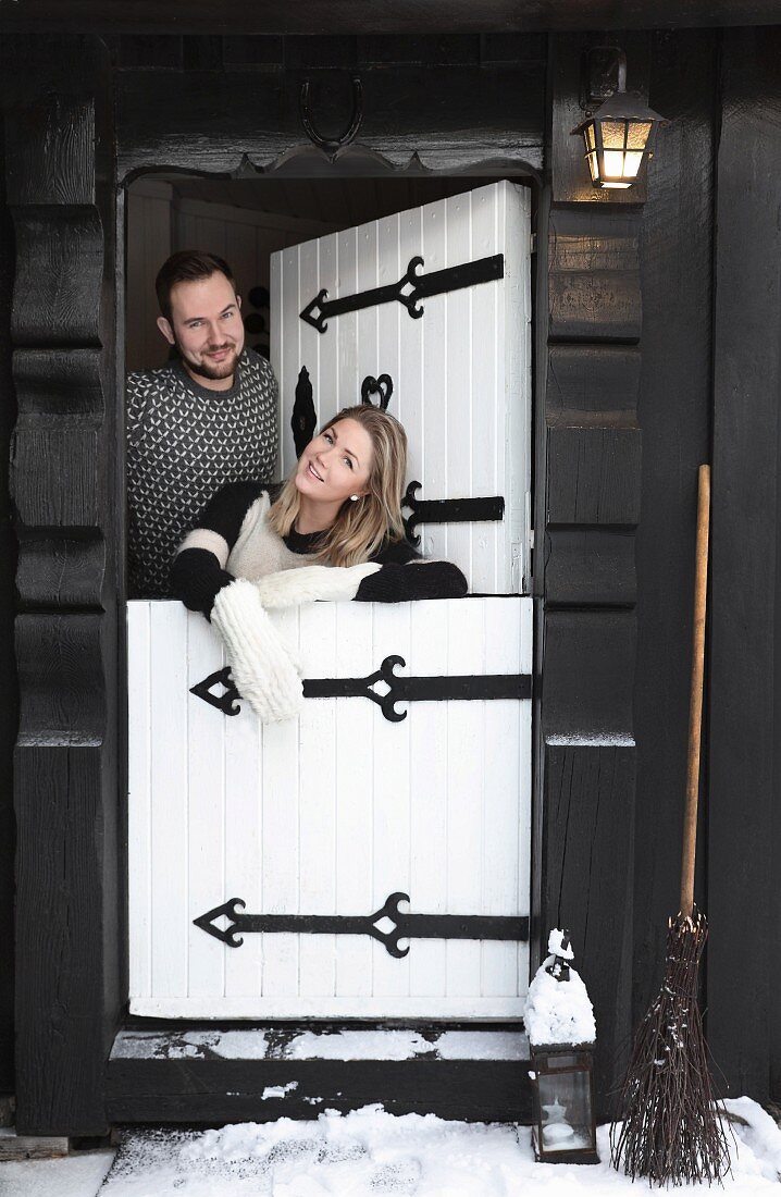 Junges Paar in einer weißen Tür zu einer schwarzen Holzhütte
