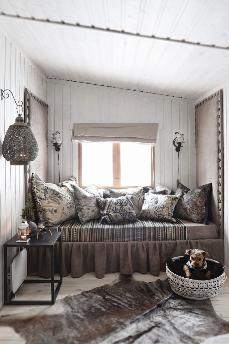 Gemütliches Tagesbett in einem kleinen Raum mit Bretterwänden