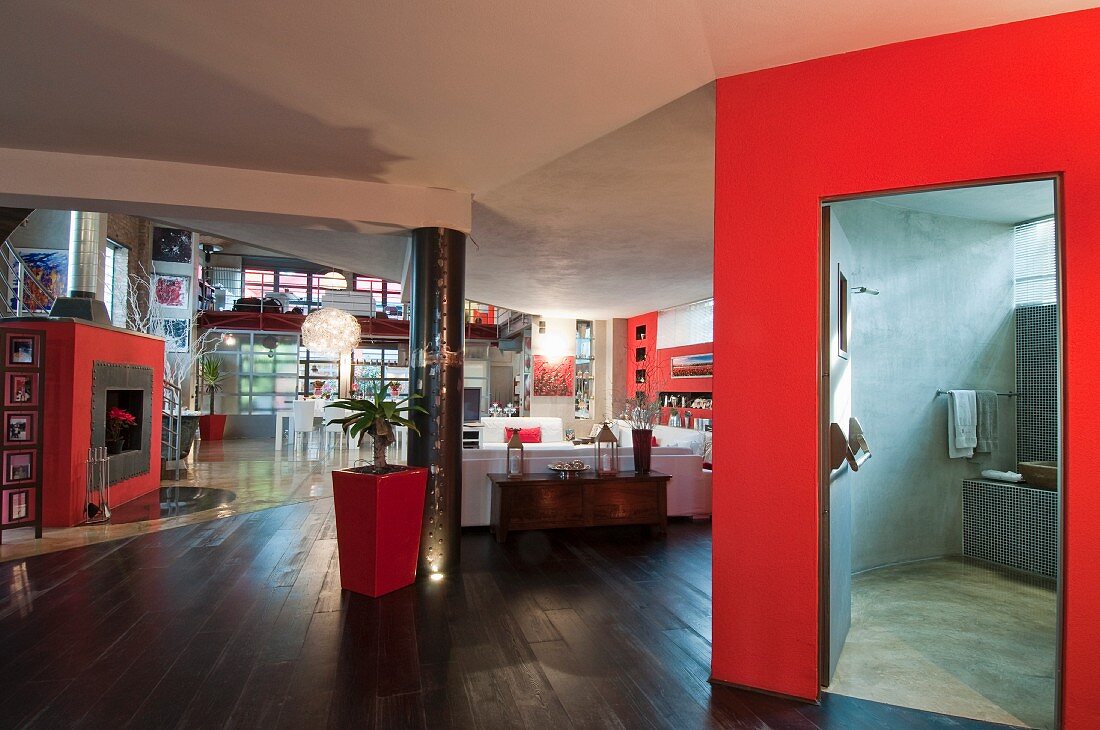 White and red furnishings in loft apartment with view into concrete-effect bathroom