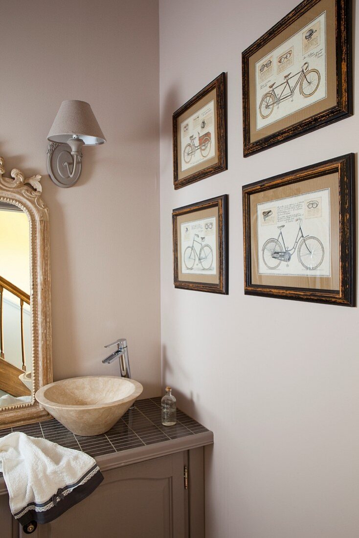 Waschtisch mit Waschschüssel und moderner Armatur in Badezimmerecke, Bildersammlung mit Fahrradmotiv an beigefarbener Wand