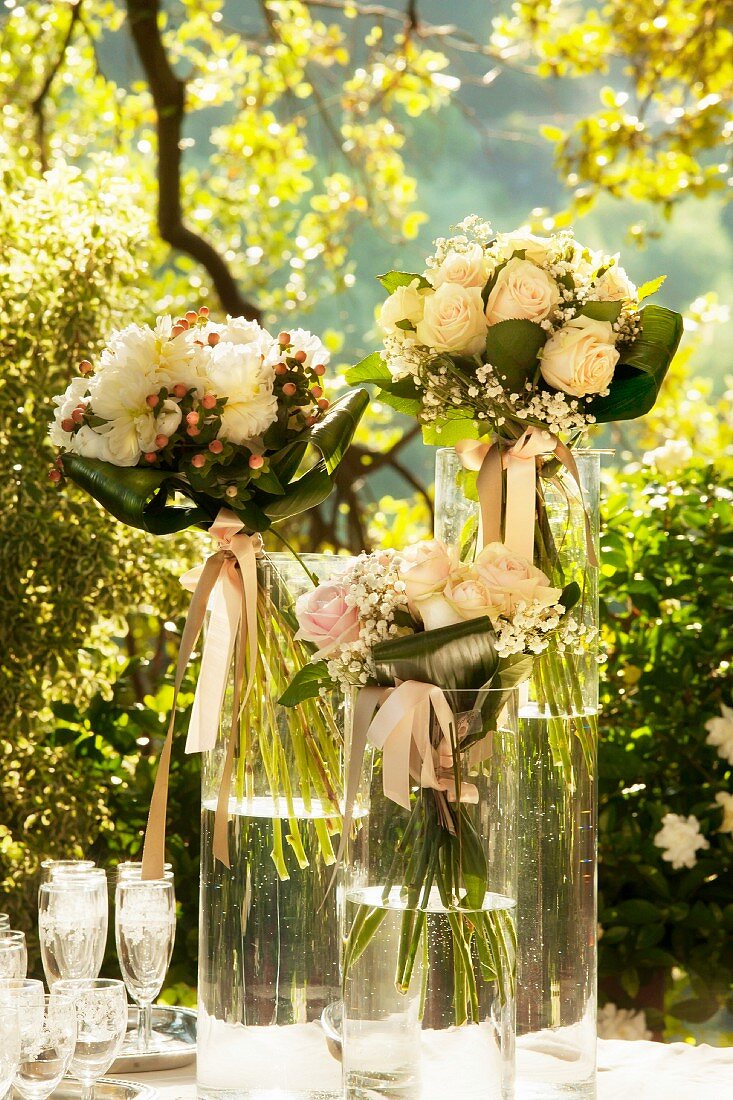 Wedding bouquets in glass vases on a outdoor table