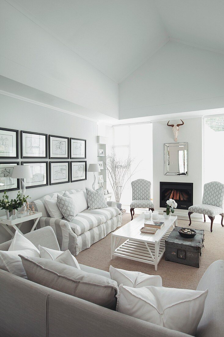 White and grey sofas, modern fireplace and antique-style upholstered chairs