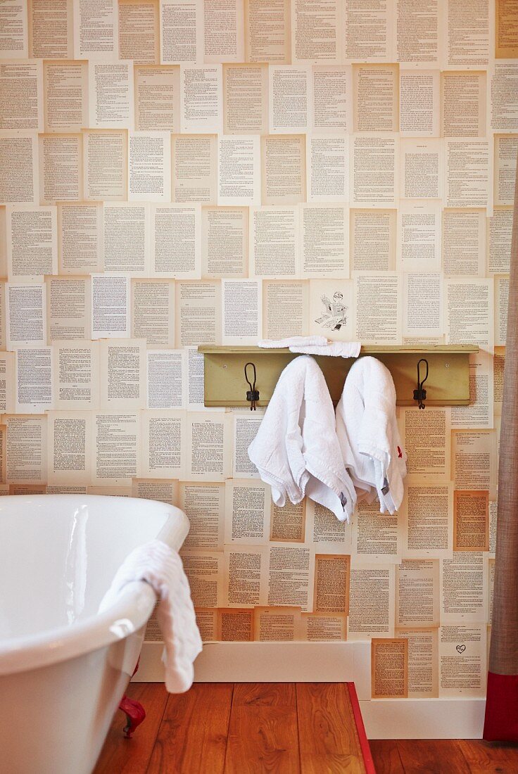 Teilweise sichtbare Badewanne neben Hakenleiste mit Ablage an tapezierter Wand