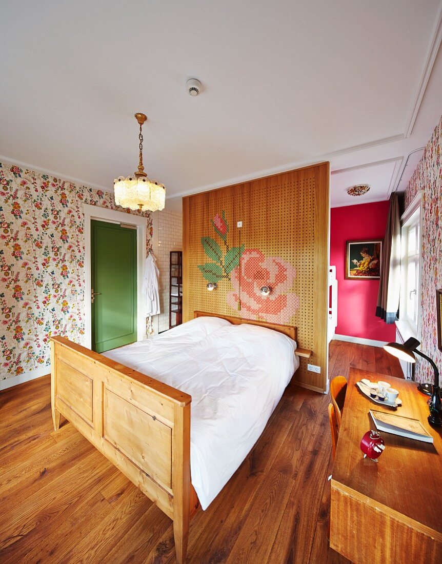In nostalgischem Hotelzimmer Doppelbett mit geschnitztem Holzrahmen vor Raumteiler, seitlich Schreibtisch