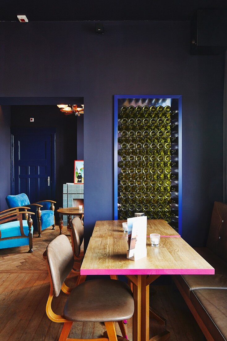 Holztisch mit pinkfarben gestrichener Kante und Stuhl mit Lederbezug in dunkelblauem Speisesaal