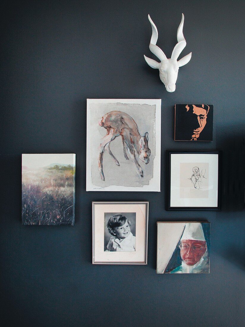 Various pictures and stylised hunting trophy on black wall