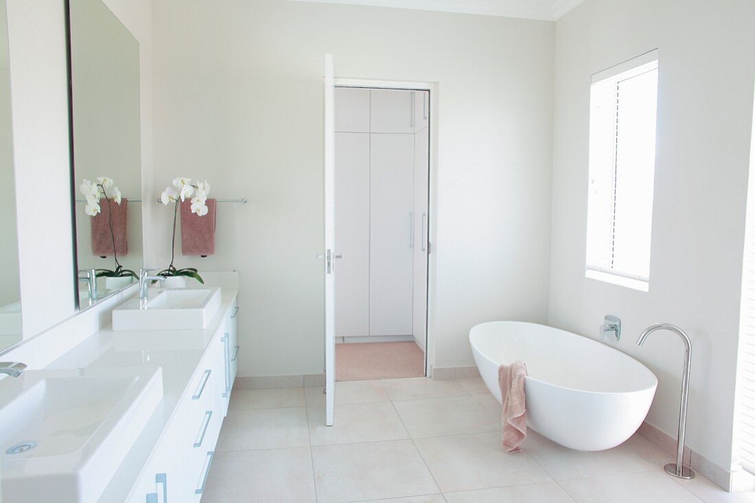 Designerwanne mit Bodenarmatur und durchgehender Waschtisch mit Aufsatzbecken in minimalistischem weißem Bad